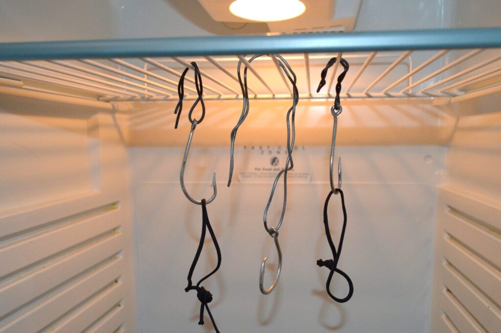 Homemade hanging hooks made from fencing wire and fish hooks inside a fridge