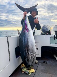 Eddie Fischer holding a 110kg southern bluefin tuna at sunset with the McLures Mogul 9in lure hanging alongside