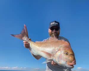 Angler holding a big Westernport snapper against a blue sky