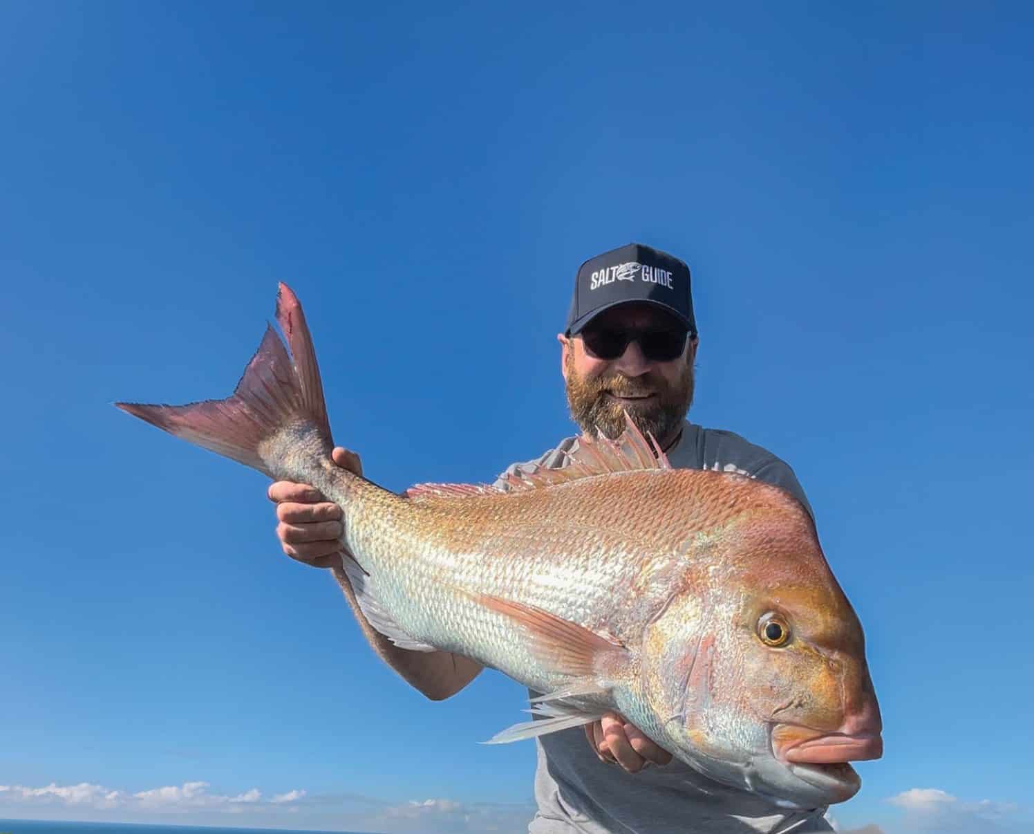 Angler holding a big Westernport snapper against a blue sky